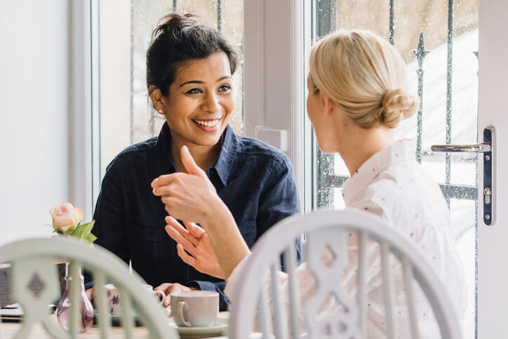 A female community support worker speaks with her female client while sitting at a table
