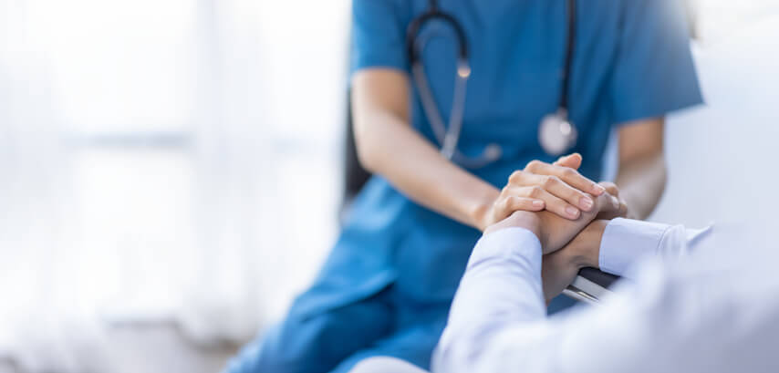 A nurse holding the hands of a patient after practical nurse training
