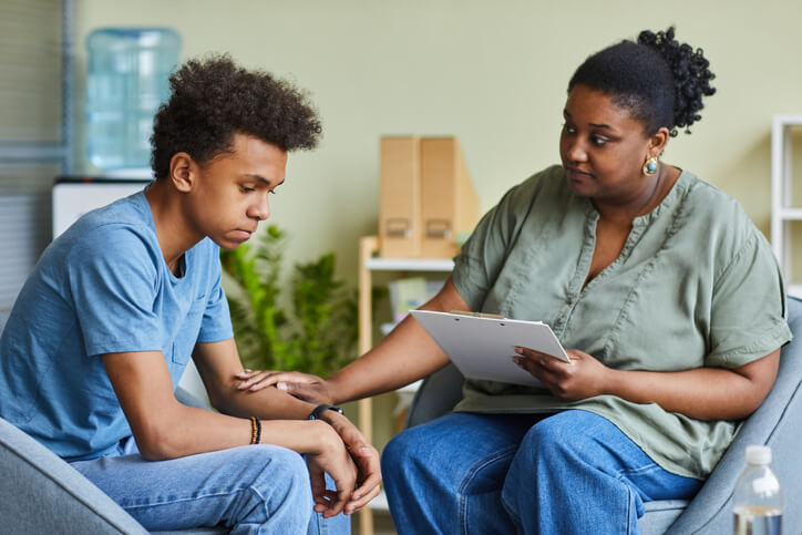 A mental health expert with a young male client in a school office after community safety training