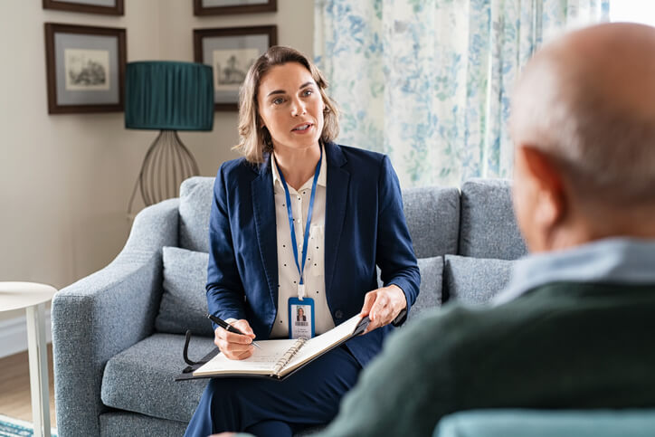 A community support worker conducting a home visit with an elderly client.
