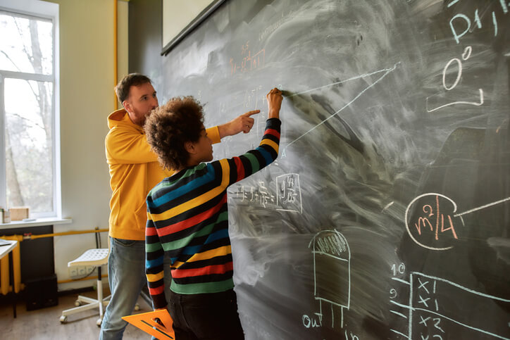 A male education assistant explaining a topic to a student after education assistant training