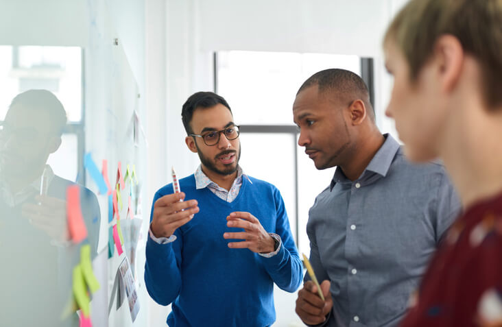 An office management training grad briefing his colleagues using a bulletin board