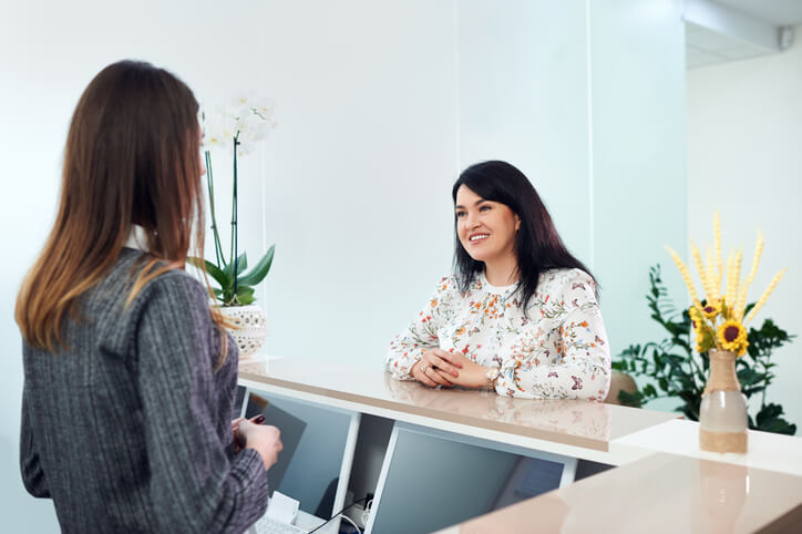 A smiling female dental receptionist in an office after completing her dental reception training