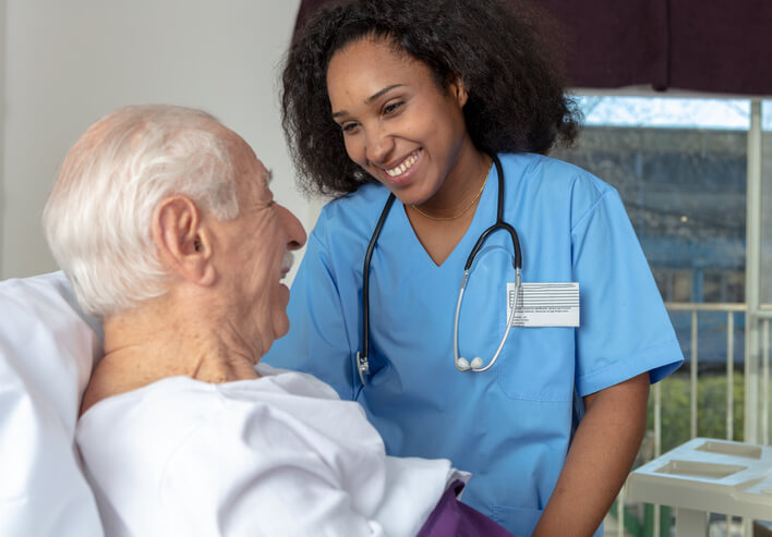 A practical nurse training graduate at a patient’s bedside