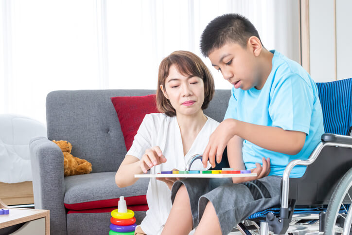A social service worker training graduate playing chess with an elderly client
