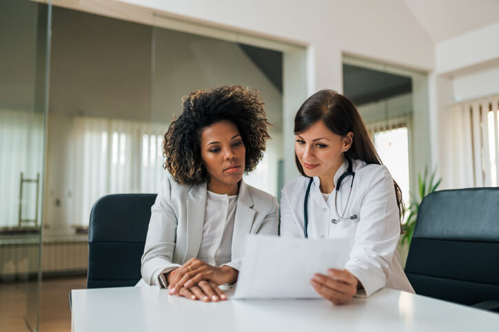 A medical office management training graduate speaking with a doctor on the job