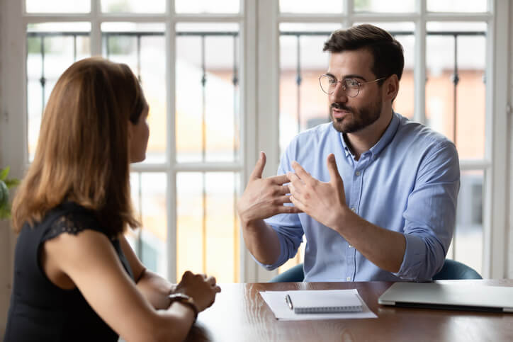 A male CEO providing performance feedback to a female employee after completing his business management and finance courses