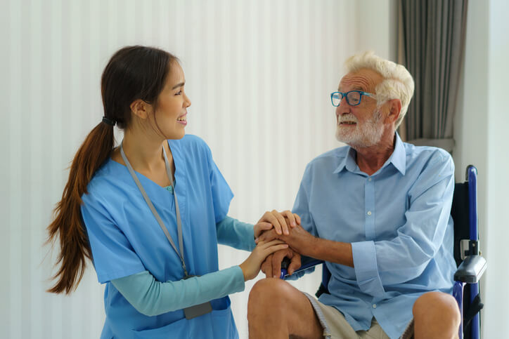 A female healthcare assistant explaining drug prescriptions to an elderly male client after completing her healthcare assistant training